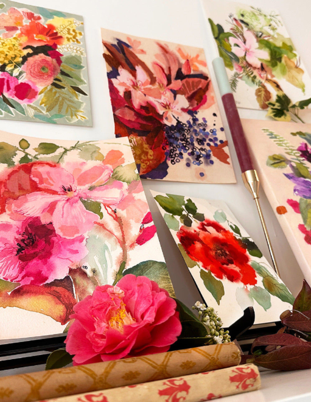 Floral-patterned notebooks and stationery items on a white surface